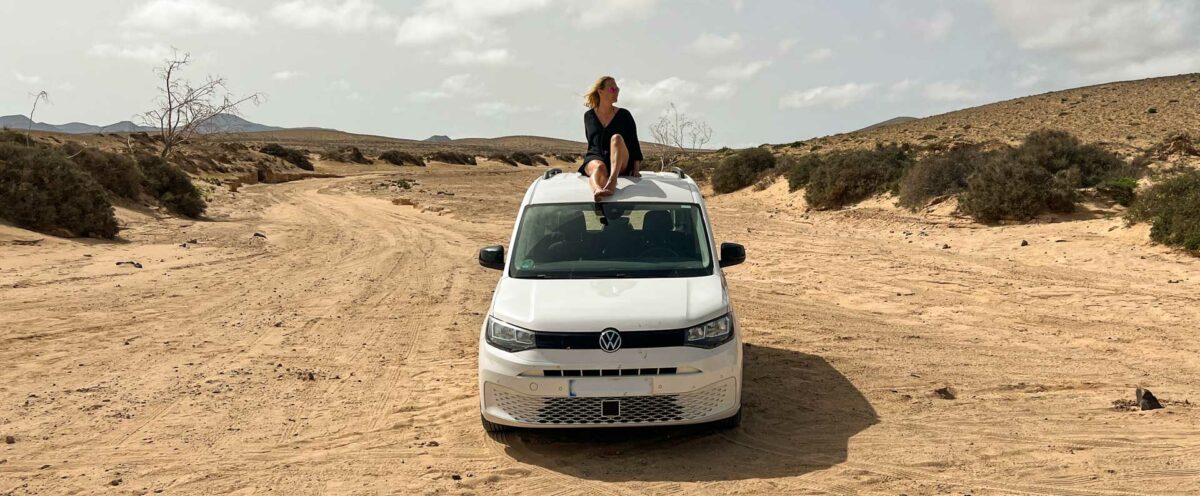 Person sitzt schlank und entspannt auf einem weißen Van in einer Wüstenlandschaft – Symbolisiert Freiheit und die Reise zu einem schlanken, gesunden Leben durch Makrotracking.