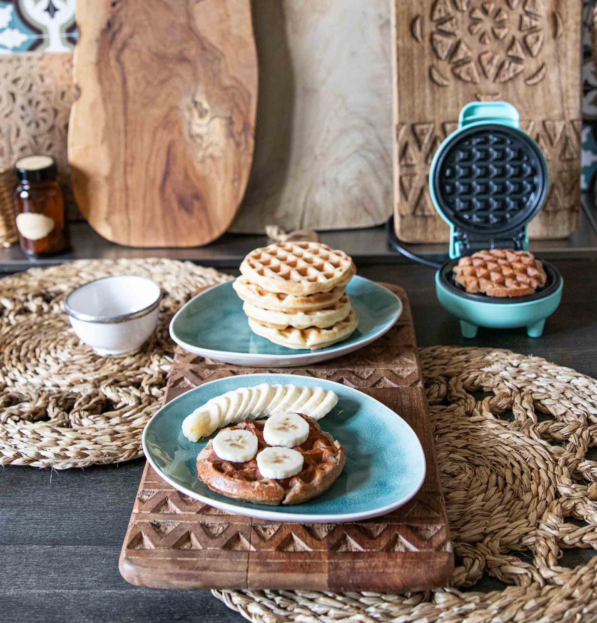 Frisch gebackene Kodiak Proteinwaffeln mit Bananen neben Waffeleisen.