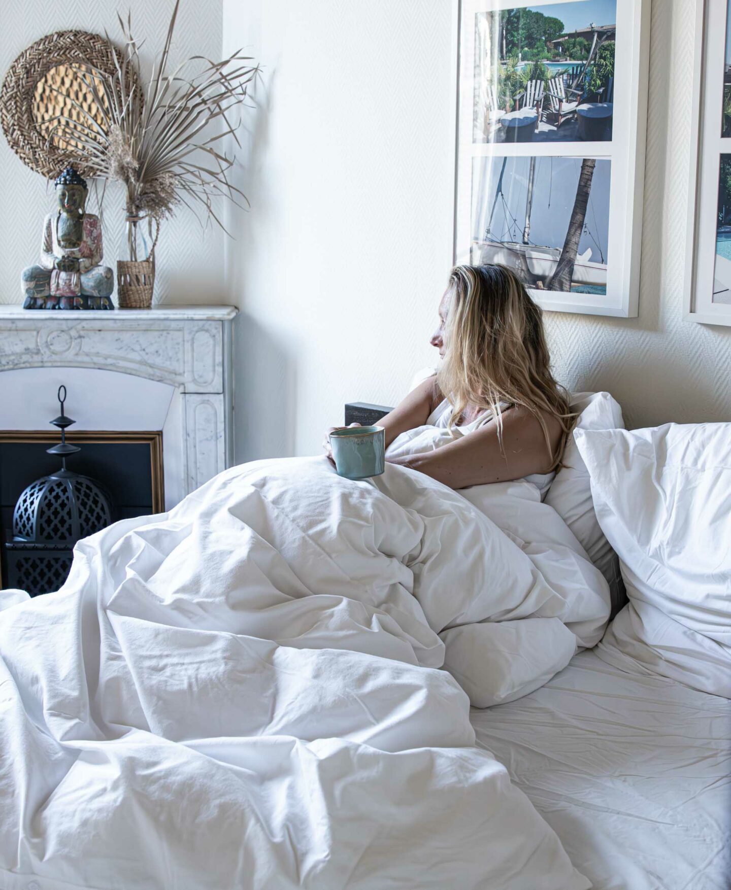 Frau mit Tasse Collagen-Kaffee sitzt entspannt im Bett