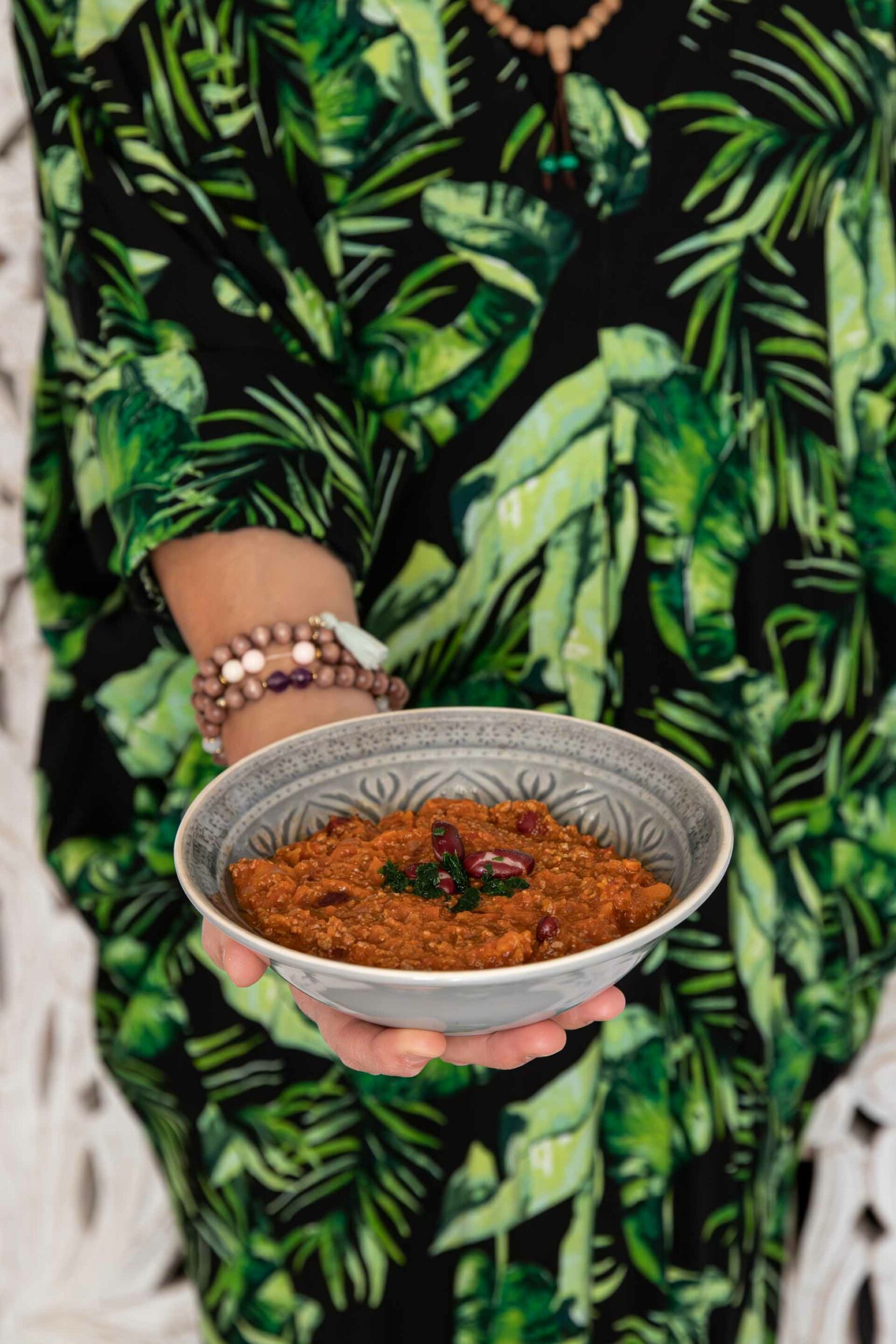 Makrofreundliches Chili mit Muskatkürbis – in einer dekorativen Schale, kohlenhydratarm und perfekt für Abnehmziele, gehalten vor einem tropischen Hintergrund