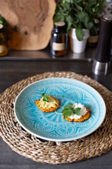 Makrofreundliche Kürbis-Rösti mit Avocado und Hüttenkäse auf blauem Teller, dekoriert mit Petersilie.