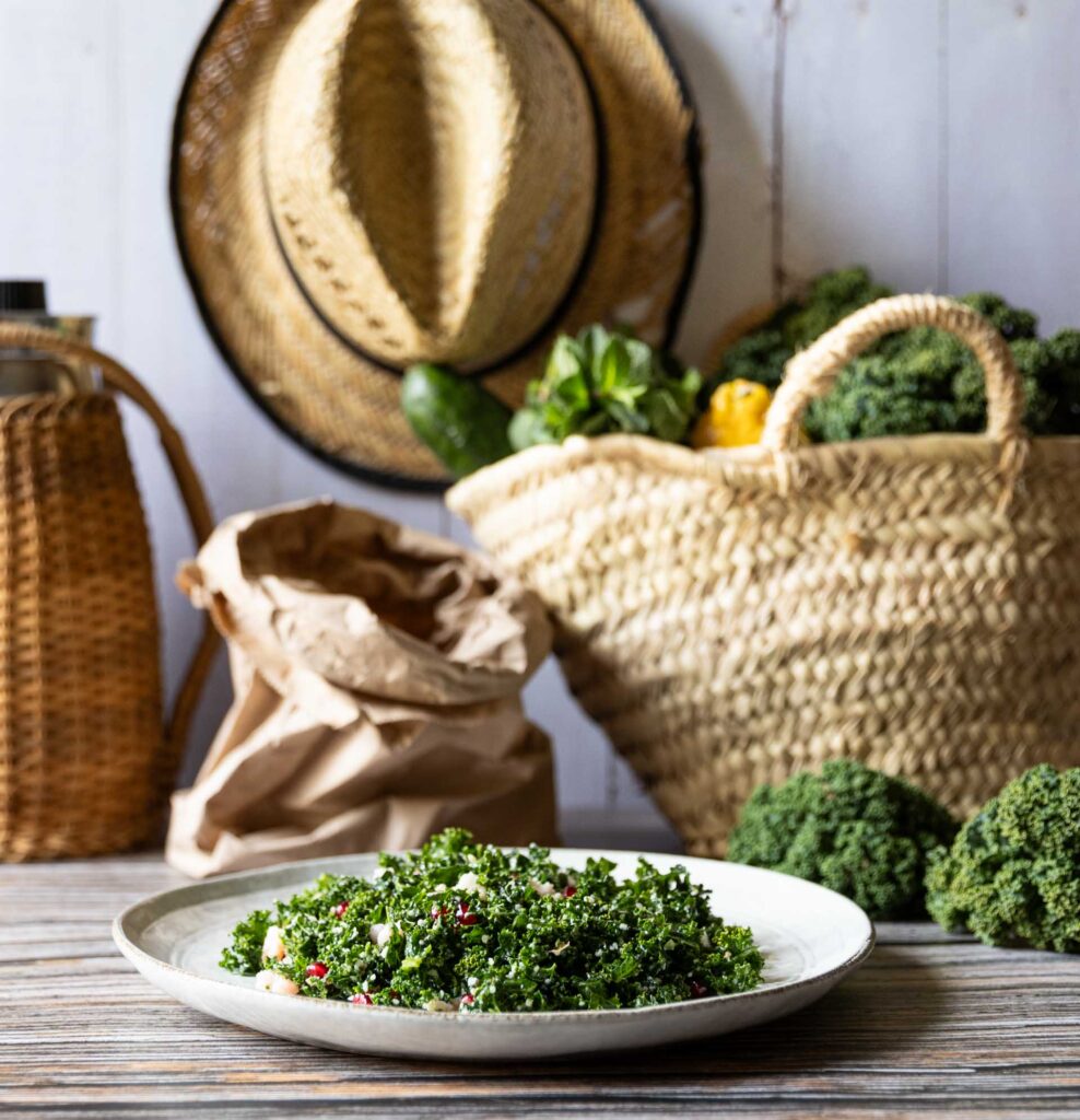 Makrofreundlicher Grünkohl-Salat mit Granatapfelkernen und Parmesan, dekoriert mit frischen Zutaten im Hintergrund