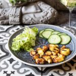 Low-Carb Fischchips mit Gemüse und Limetten-Minz-Getränk auf einem Fliesentisch.