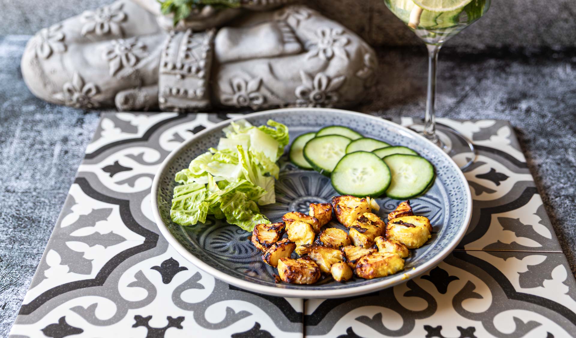 Low-Carb Fischchips mit Gemüse und Limetten-Minz-Getränk auf einem Fliesentisch.