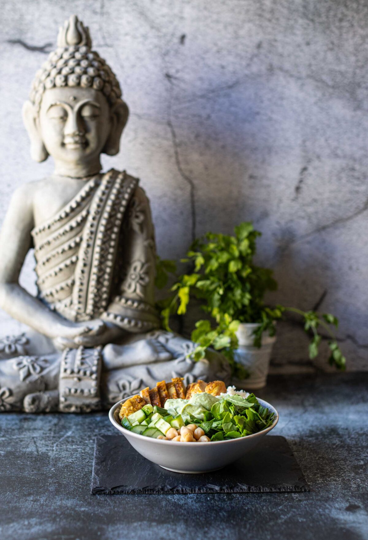 Low Carb Bowl mit Hähnchen und Gemüse vor Buddha-Deko.