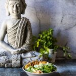 Low Carb Bowl mit Hähnchen und Gemüse vor Buddha-Deko.
