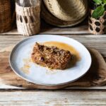 Zucchini-Lasagne Low Carb mit Käsekruste auf Teller, rustikale Umgebung