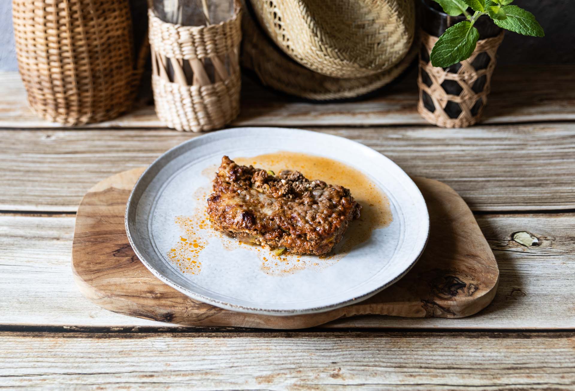 Zucchini-Lasagne Low Carb mit Käsekruste auf Teller, rustikale Umgebung