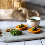 Petersilien-Walnuss-Pesto auf Süßkartoffel mit Walnüssen auf Servierbrett