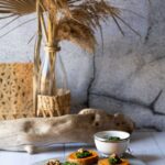 Servierplatte mit Pesto-Scheiben und Dekoration im Hintergrund