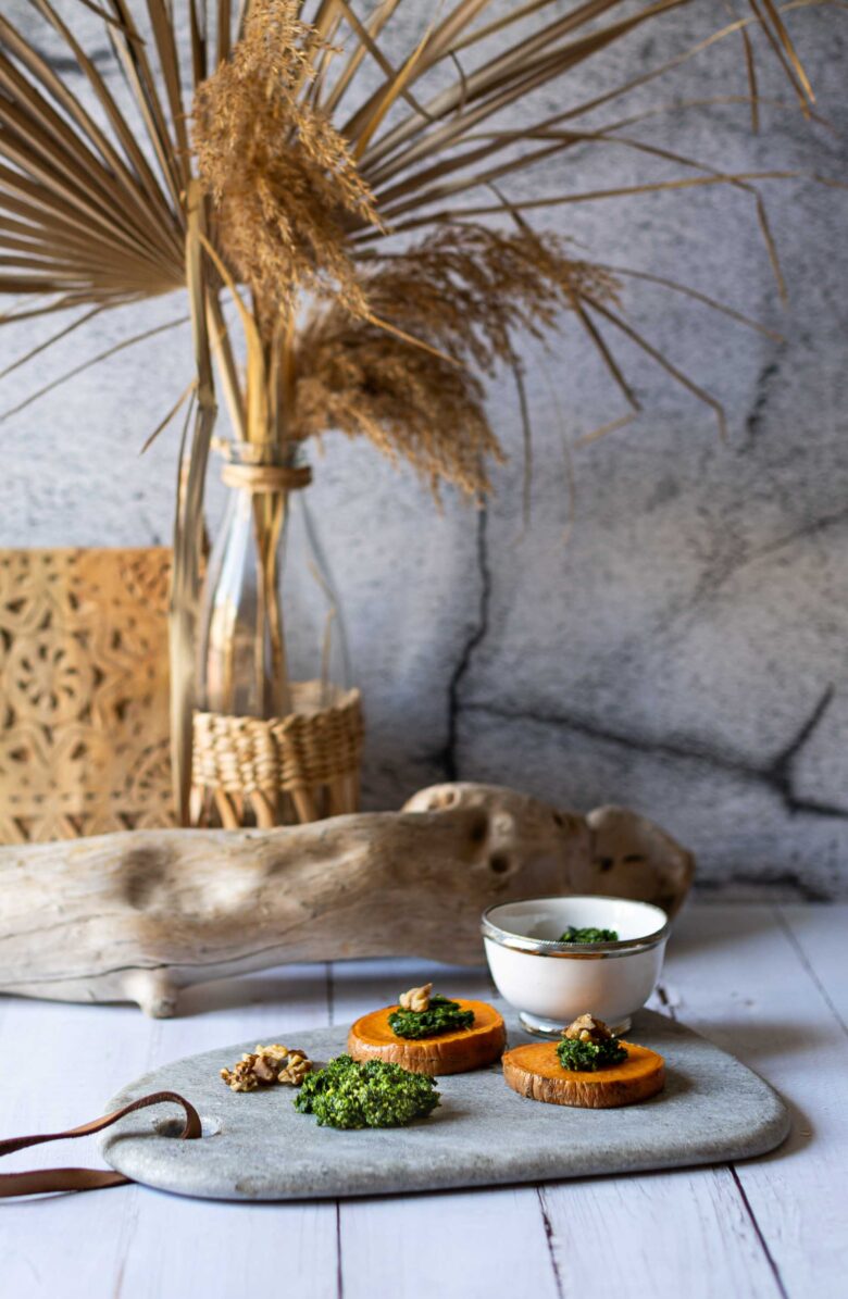 Servierplatte mit Pesto-Scheiben und Dekoration im Hintergrund