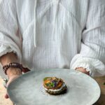 Makrofreundliches Süßkartoffel-Rote-Bete-Türmchen mit Hüttenkäse, Pesto und Blüten, serviert auf hellem Teller